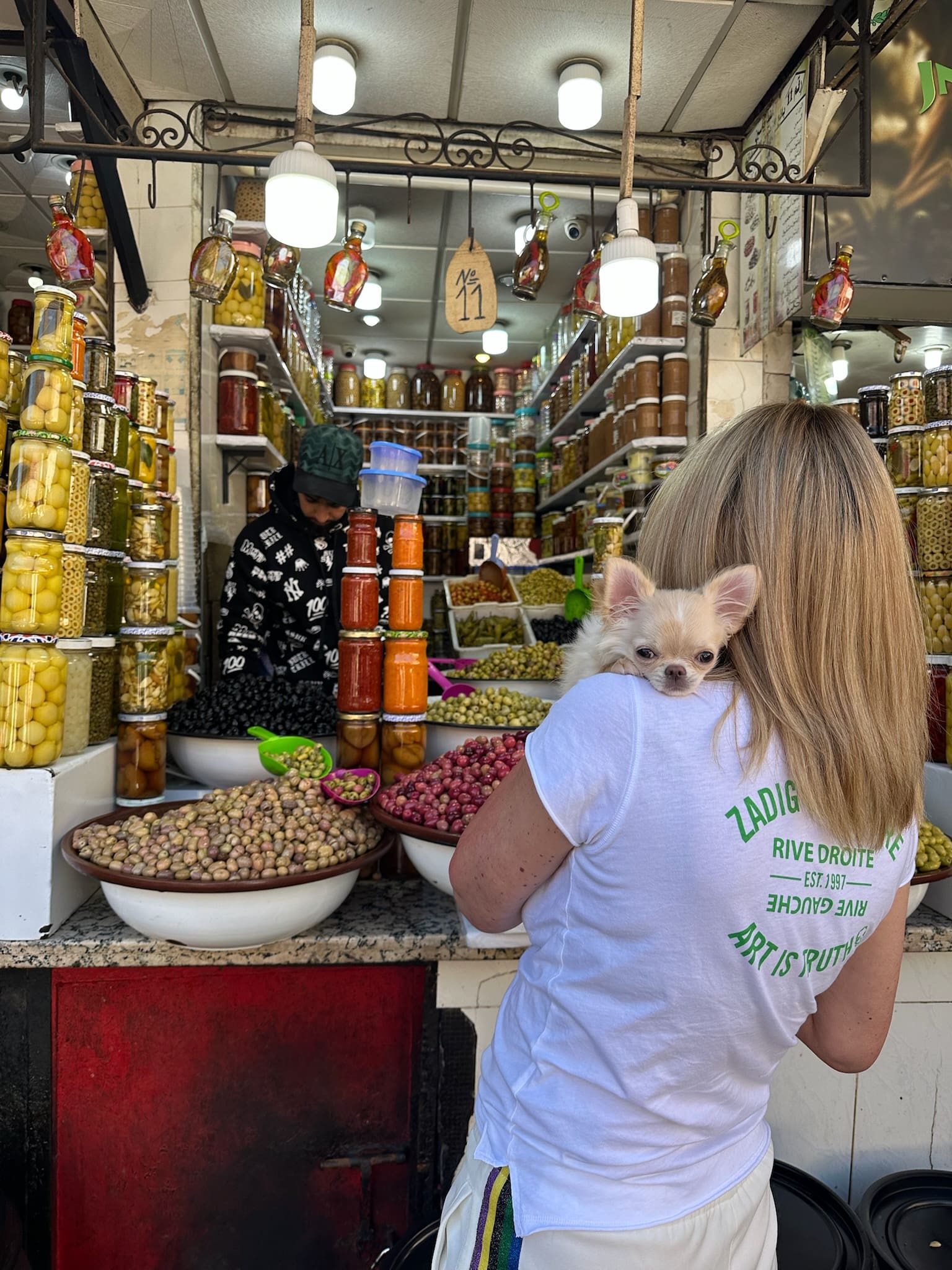 Dr. Sydney Ceruto carrying chihuahua Gisela through authentic Moroccan market showcasing global lifestyle and connection